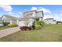 Charming two-story home with a well-manicured lawn, complemented by beautiful landscaping and a colorful front garden at 6699 Alder Rd, Harmony, FL 34773