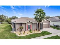 Charming single-story home features a well-manicured lawn, a palm tree, and a two-car garage at 901 Shorehaven Dr, Poinciana, FL 34759