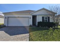 Charming single-story home featuring a well-manicured lawn, a two-car garage, and inviting curb appeal at 1046 Wanderer Dr, Deltona, FL 32738