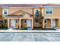 Charming two-story townhomes showcasing terra cotta tile roofs, white trim, covered entrances and landscaped front yards at 2606 Roadster Ln, Kissimmee, FL 34746