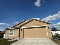 Tan home featuring an attached two car garage with tan doors and nicely landscaped yard at 299 Chicago W Ave, Haines City, FL 33844