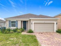 Charming single-story home with a brick driveway, a two-car garage, and blue shutters at 417 Tisone Ln, Davenport, FL 33837