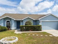 Charming single-story home featuring a well-manicured lawn, garden, and a two-car garage at 790 Greenshank Dr, Haines City, FL 33844