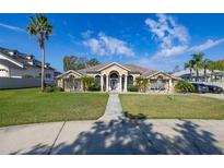 Beautiful home with lush front lawn, mature palms, and inviting walkway to the front door at 10919 Lakeshore Dr, Clermont, FL 34711