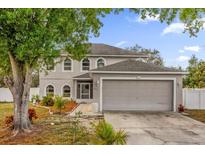 Two-story home with a neutral color scheme, arched windows, and well-maintained landscaping at 241 Cranbrook Dr, Kissimmee, FL 34758