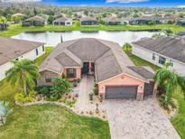 Stunning aerial view of home with lake, lush landscaping and a paved driveway leading to a two-car garage at 484 Villa Park Rd, Kissimmee, FL 34759