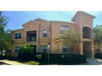 Lovely condo building featuring stucco exterior, second floor balcony, and lush green landscaping at 501 Terrace Ridge Cir # 501, Davenport, FL 33896