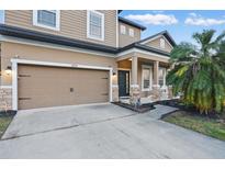 A tan two-story home featuring a garage and front porch with brick pillars, offering curb appeal at 1894 Valley Forge Dr, St Cloud, FL 34769