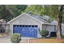 Charming single-story home featuring a striking blue garage door and a well-maintained lawn at 1021 Royal Oaks Dr, Apopka, FL 32703