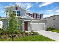 Two-story home featuring a two-car garage, a red front door, well-maintained lawn and landscape, and light gray paint at 1111 Olivine Ave, Dundee, FL 33838