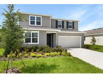 Charming two-story home featuring a two-car garage, beautiful landscaping, and a welcoming front entrance at 1127 Olivine Ave, Dundee, FL 33838