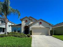 Charming single-Gathering home with a manicured lawn and a two-car garage under a clear, blue sky at 12369 Sawgrass Prairie Loop, Orlando, FL 32824