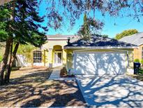 Charming single-story yellow home with a two-car garage and manicured front yard, perfect for suburban living at 12622 Earnest Ave, Orlando, FL 32837