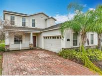 Charming two-story home with brick driveway, attached garage, and a well-manicured lawn with lush tropical landscaping at 15147 Driftwood Bend St, Winter Garden, FL 34787