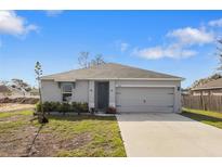 Charming single-story home featuring a two-car garage, freshly painted exterior, and a well-manicured front lawn at 408 Danube Dr, Poinciana, FL 34759