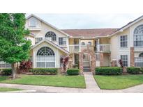 Charming condo with a yellow exterior, brick archway entrance, and well-manicured landscaping at 5012 Laguna Bay Cir # 74, Kissimmee, FL 34746