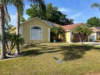 Charming single-story home featuring a well-manicured lawn, a two-car garage and lush tropical landscaping at 701 Swallow Ln, Poinciana, FL 34759