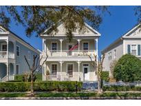 Charming two-story home with a double front porch, white railings, and manicured landscaping at 826 Lake Evalyn Dr, Celebration, FL 34747