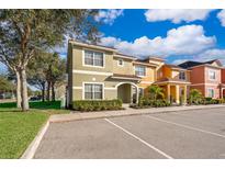 Beautiful multi-colored townhouses with covered front entryways and well manicured shrubs, on a sunny day at 8949 Candy Palm Rd, Kissimmee, FL 34747