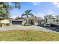 Charming single-story home with a well-manicured lawn, palm tree, two-car garage, and long driveway at 11812 Lakeshore Dr, Clermont, FL 34711