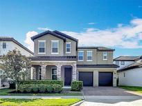 Stunning two-story home with stone accents, a well-manicured lawn, and an attached two-car garage at 12880 Westside Village Loop, Windermere, FL 34786