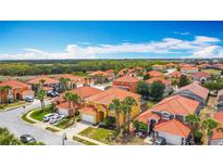 Expansive aerial view of a residential neighborhood with orange tile roofs and lush landscaping on a sunny day at 131 Stella Pass, Davenport, FL 33837