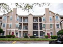 Tan condo building with multiple stories, balconies, and well-manicured landscaping creating an inviting curb appeal at 1990 Erving Cir # 207, Ocoee, FL 34761
