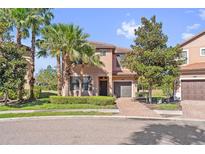 Charming two-story home featuring tropical landscaping, a brick driveway, and an attached garage at 5512 Solterra Cir, Davenport, FL 33837