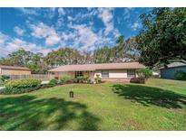 Charming single-story home featuring a lush green lawn and neatly landscaped garden beds beneath a cloudy blue sky at 6449 Eve St, St Cloud, FL 34771