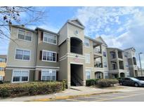 Modern condominium exterior with tan siding, red shutters, and well-maintained landscaping under a blue sky at 8137 Claire Ann Dr # 203, Orlando, FL 32825