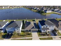 Aerial view of a house near a lake in a neighborhood with well-maintained lawns at 1524 Venice Ln, Davenport, FL 33896