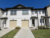 A modern two-story townhome with a two-car garage and well-manicured lawn at 1613 Pelican Dr, Davenport, FL 33896
