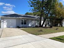 Charming one-story home featuring a well-manicured lawn, long concrete driveway, and an attached single-car garage at 305 S Palm Ave, Kissimmee, FL 34741