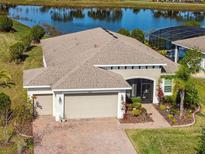 Beautiful home featuring a three-car garage, lush landscaping, and a serene waterfront view at 4311 Via Cavour Ct, Kissimmee, FL 34759