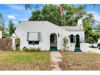 Charming white home with green trim, arched doorway, awning, flagpole, and unique textured facade at 528 S 8Th St, Lake Wales, FL 33853