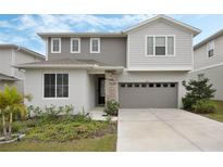 Two story home with a gray two car garage, stone accents and manicured landscaping at 1108 Sugarwood St, Davenport, FL 33837