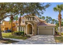 Charming two-story home with tile roof, arched entry, and well-manicured landscaping at 113 Tiger Lily Ct, Davenport, FL 33837