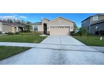 Charming single-story home featuring a manicured lawn and a two-car garage at 14112 Queenside St, Orlando, FL 32824