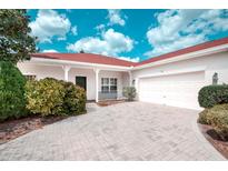 Charming single-story home with a two-car garage, red roof and a well-manicured lawn, all under a sunny, partly cloudy sky at 318 Rock Springs Dr, Poinciana, FL 34759