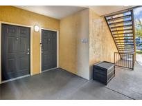 Condo entrance with two gray doors, stairs, and seating area at 6153 Metrowest Blvd # 103, Orlando, FL 32835