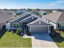 Front exterior view of a well-manicured home with a gray exterior and two-car garage at 649 Meadow Pointe Dr, Haines City, FL 33844
