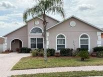 Charming single-story home with a well-manicured lawn, brick driveway and a healthy palm tree in the front yard at 153 Cambridge Ave, Davenport, FL 33896