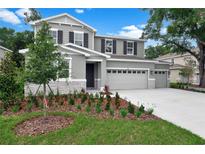 Two-story home featuring a three car garage, gray paint, black shutters and a well maintained lawn at 3741 Deer Ridge Dr, Mount Dora, FL 32757