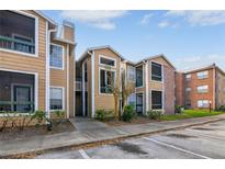 Two-story condo with tan siding, well-maintained landscaping and visible parking area at 5530 Chrishire Way # D204, Orlando, FL 32822