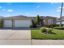 Charming single-story home featuring a spacious three-car garage, lush lawn, and beautiful landscaping at 141 Prestwick Dr, Davenport, FL 33897