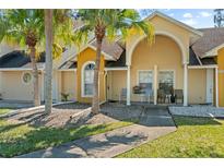 Inviting townhome exterior with lush landscaping, palm trees, and a cozy front porch sitting area at 3112 Enclave Ct, Kissimmee, FL 34746