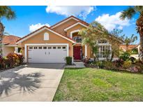 Charming home featuring a red-tiled roof, complemented by a well-manicured lawn, a two car garage, and colorful front yard landscaping at 413 Paloma Dr, Davenport, FL 33837