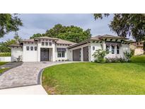 Stunning modern home showcasing a beautiful front lawn, a paver driveway, and a crisp white exterior at 13049 Sunshine Cir, Clermont, FL 34711