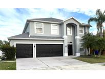Two-story home featuring a three-car garage and well-manicured landscaping at 1713 Brassie Ct, Kissimmee, FL 34746