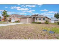 Charming single-story home featuring tan siding, well-maintained lawn and a two car attached garage at 251 Tower View W Dr, Haines City, FL 33844